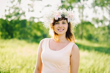 başında çiçek çelenk gülümseyen güzel genç kız