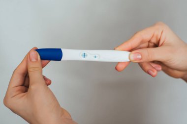 hamile bir kız elinde pozitif gebelik testi