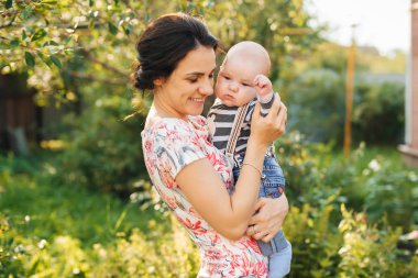 Mutlu genç beyaz anne gülümseyerek elinde bir çocuk yeni doğan oğluyla