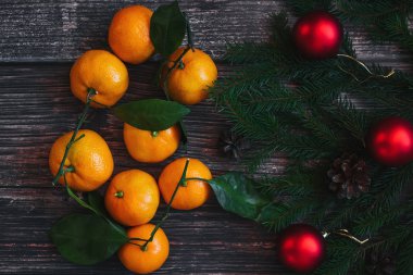 Mandarins, köknar dalları, kırmızı topları ve ahşap masa üzerinde çam kozalağı ile Noel arka plan. Geleneksel şenlikli kış dekoru