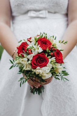 gelinin elinde kırmızı ve beyaz güller ile düğün buketi