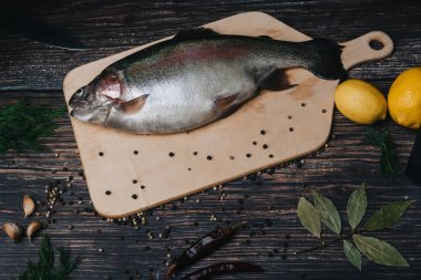 Mutfakta rustik tarzda ahşap bir masada bir tahta üzerinde çiğ alabalıklar
