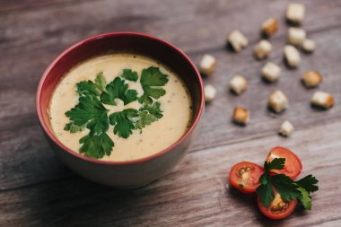 Maydanoz domates ve kraker ile ahşap bir masa üzerinde bir kase ile sebze vejetaryen kabak krem çorbası.