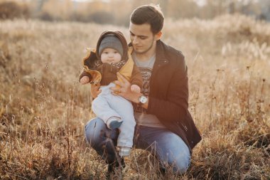 Sonbaharda doğada oturan oğluyla genç bir baba.
