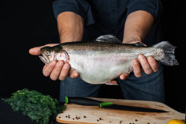 Alabalık mutfak arka plan üzerinde bir adamın elinde. Şef ile büyük taze balık