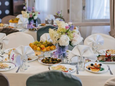 beyaz bir masa örtüsü üzerinde tabak, gözlük ve Çatal ile restoranda şenlikli masa