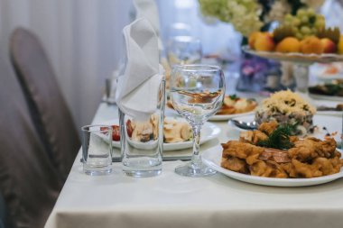 beyaz bir masa örtüsü üzerinde tabak, gözlük ve Çatal ile restoranda şenlikli masa