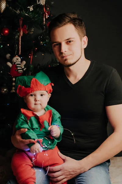 Papà caucasico con la barba con un bambino tra le braccia sullo sfondo di un albero di Natale — Foto Stock