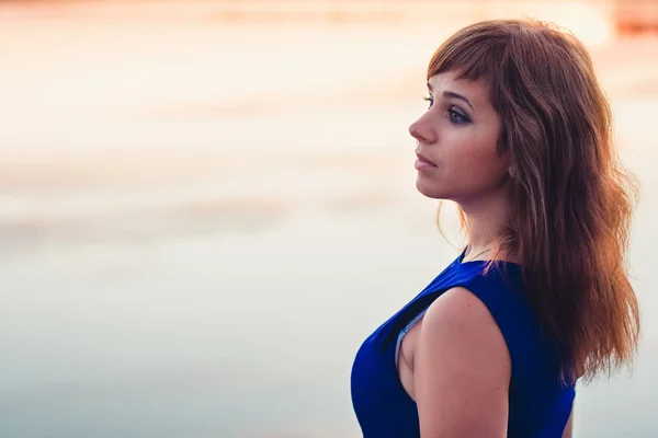 Chica en vestido azul posando sobre un fondo de puesta de sol —  Fotos de Stock