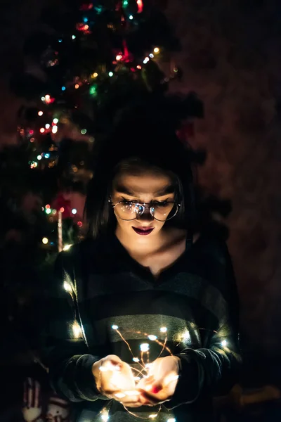 自宅で夜にライトで花輪を保持する眼鏡を持つ女の子 — ストック写真