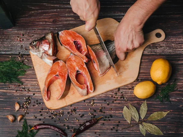 Trucha en el tablero, que corta a un hombre cocinar con un cuchillo. Pescado rojo crudo fresco — Foto de Stock