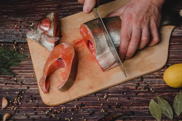 El hombre corta una trucha con un cuchillo en una tabla. Pescado crudo fresco — Foto de Stock