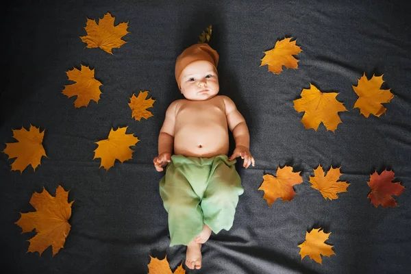 Un nouveau-né allongé avec des feuilles d'érable. Concept d'enfance d'automne — Photo