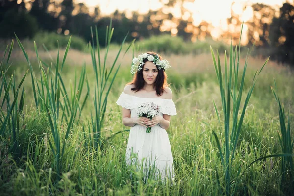 Menina em um vestido branco com uma grinalda e um buquê de flores — Fotografia de Stock