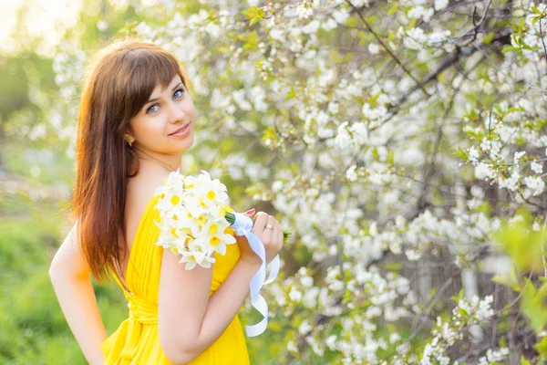 Bella ragazza sorridente con un mazzo di fiori all'aperto in primavera — Foto Stock