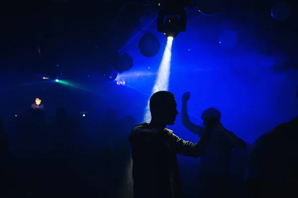 Silhouetten von Menschen, die bei einer Party in einem Nachtclub auf der Tanzfläche tanzen — Stockfoto