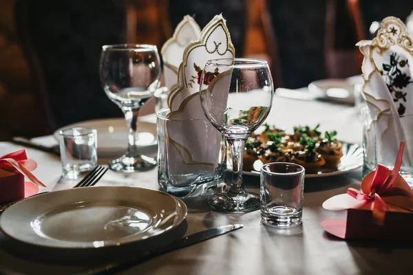 Ensemble de verres vides et assiettes avec couverts sur une nappe blanche sur la table dans le restaurant — Photo