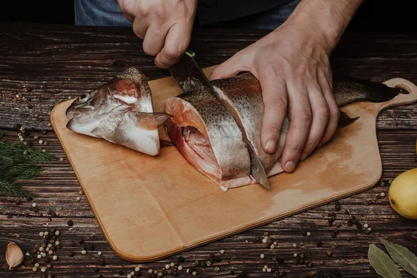 Hombre cocina cortes con un cuchillo para cocinar trucha fresca —  Fotos de Stock