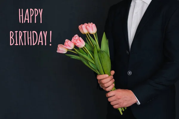 Boeket van roze bloemen van tulpen in mannen handen. Wenskaart met de inscriptie Happy Birthday — Stockfoto