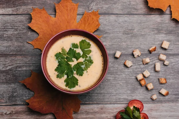 Gemüse-vegetarische Kürbiscremesuppe mit Petersilie in einer Schüssel auf einem Holztisch mit Tomaten und Crackern. — Stockfoto