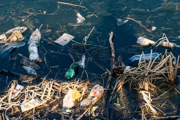 VICHUGA, RUSIA - 21 DE ABRIL DE 2019: Varias basuras y desechos de botellas y bolsas de plástico en el agua y en la orilla del río —  Fotos de Stock