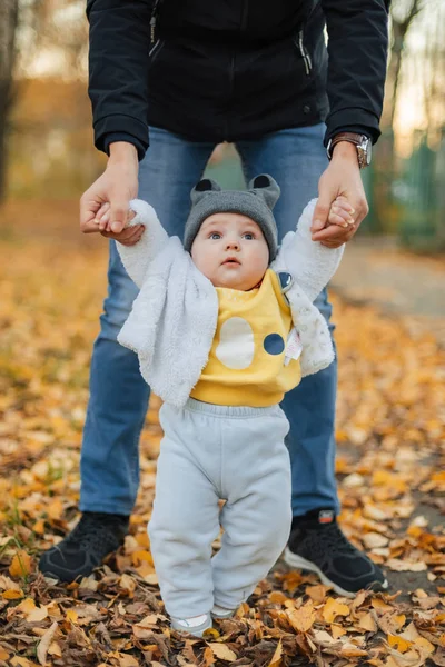 Kleine baby jongen leert om de eerste stappen te nemen houden dad's handen — Stockfoto