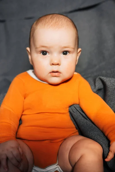 Egy narancssárga Body kisfiú ül — Stock Fotó