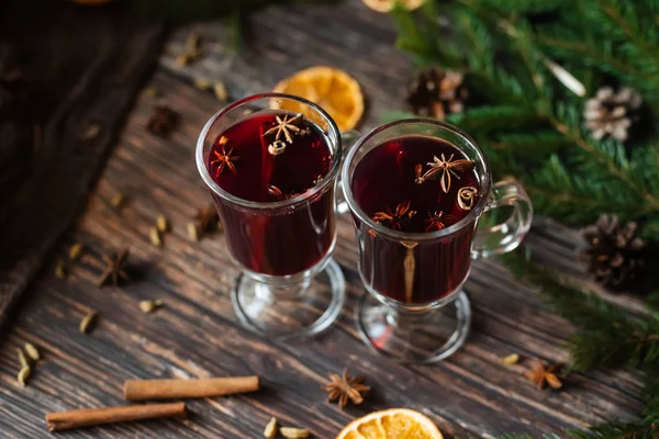 Dos copas con vino caliente en la mesa con rodajas de naranja y especias —  Fotos de Stock