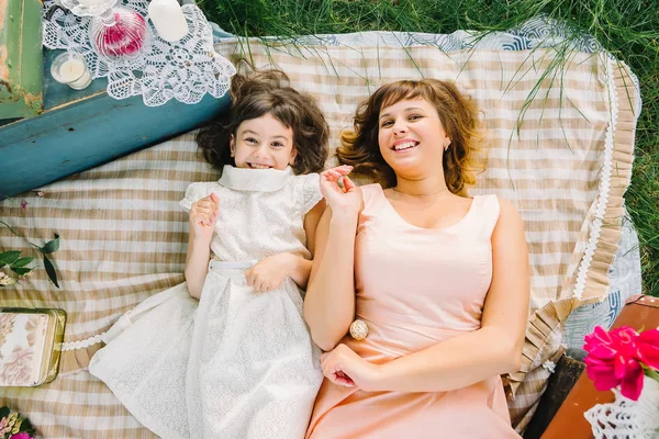 Счастливые мать и дочь играют и улыбаются, лежа на одеяле летом — стоковое фото