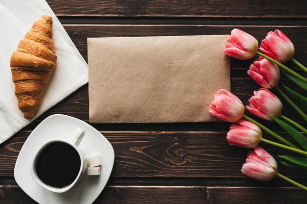 Tasse Kaffee mit einem Strauß rosa Tulpenblüten und einem Croissant für das Frühstück am Morgen — Stockfoto