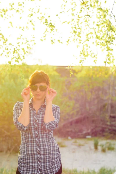Молодая девушка в солнечных очках и рубашке на закате — стоковое фото
