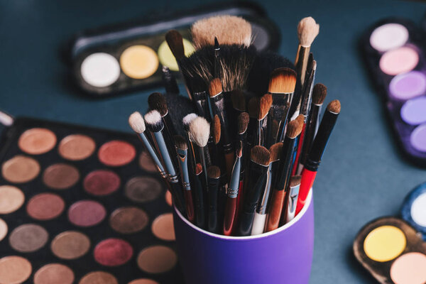 set of makeup brushes on the background of a professional palette with eye shadows