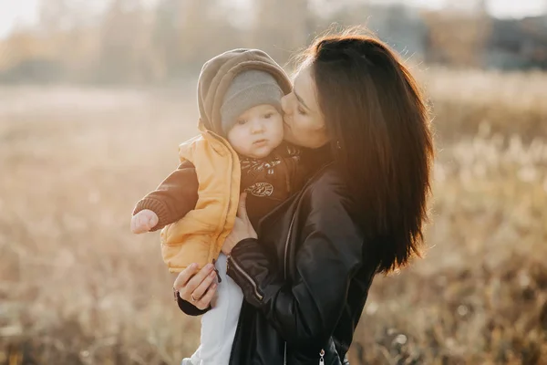 Gioioso felice giovane madre con il suo bambino ragazzo figlio nelle sue mani in autunno — Foto Stock