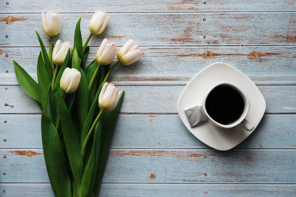 Weißer Tulpenstrauß auf blauem Holzgrund mit einer Tasse Kaffee — Stockfoto