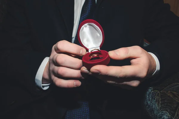 Twee Gouden trouwringen liggen in een rode doos op de mannelijke hand — Stockfoto