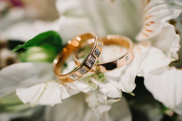 Két arany jegygyűrű gyémántokkal feküdjön egy virágos csokor — Stock Fotó