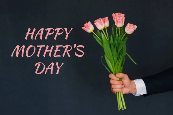 Boeket van roze tulpen in het geven van een man. Wenskaart met tekst Happy mother's Day — Stockfoto