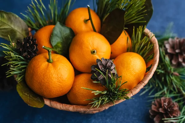 Çam dallarıyla süslenmiş ahşap bir sepette mandalinalar.