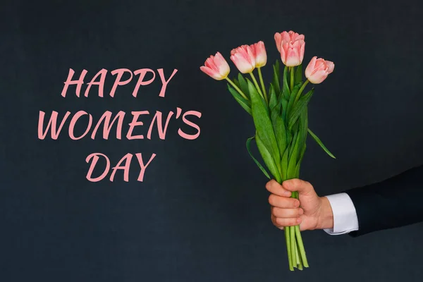 Μπουκέτο ροζ τουλίπες στο χέρι ενός άντρα. Ευχετήρια κάρτα με κείμενο ευτυχισμένη μέρα των γυναικών — Φωτογραφία Αρχείου