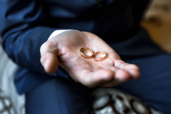 Duas alianças de casamento de ouro nas mãos do homem — Fotografia de Stock