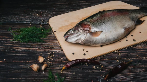 RAW pstrąg na pokładzie na stole z składniki do gotowania. świeże ryby czerwone — Zdjęcie stockowe