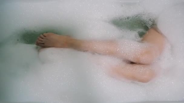 Bela morena menina sexualmente acaricia sua perna e canta no banheiro com espuma — Vídeo de Stock