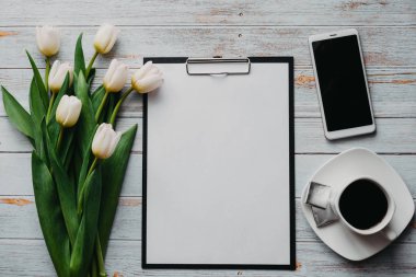 Beyaz lale buketi, ahşap mavi arka planda, kahve fincanı, akıllı telefon ve boş kağıt tablet.