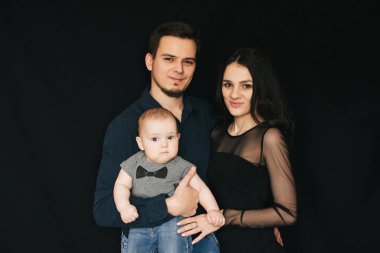 Genç siyah bir zemin üzerine beyaz aile. Mutlu baba, anne ve oğul. Seven bir çocuk tutan çift.