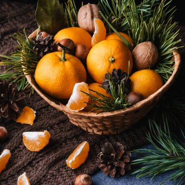 Çam kozalakları ve dallarla süslenmiş mandalina, ceviz ve fındık.