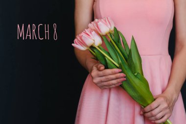 Bir kızın elinde pembe lale çiçek buketi. Metin ile tebrik kartı 8 Mart