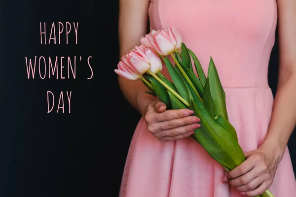 Bouquet of flowers of pink tulips in the hands of a girl. Greeting card with text Happy Women's Day — Stock Photo, Image