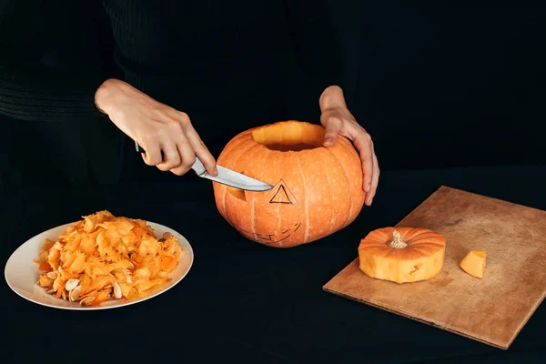 Halloween. Flickans händer med en kniv styckning orange pumpa — Stockfoto