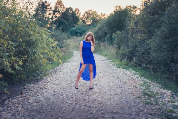 日没を背景にポーズ青いドレスの女の子 — ストック写真