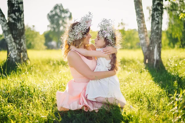 Mamma abbraccia sua figlia seduta sull'erba all'aperto in un'estate soleggiata — Foto Stock